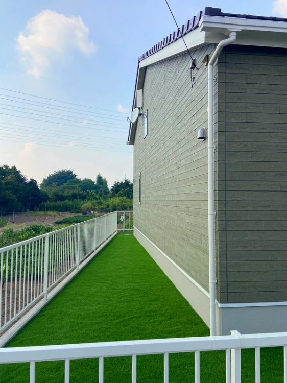 新築外構　オレンジ色のアプローチと人工芝の緑が映える施工例